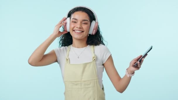 Dançando, música e mulher feliz em fones de ouvido no celular em estúdio isolado em um espaço de fundo azul mockup. Rádio, sorriso e pessoa ao telefone movendo-se para o áudio, ouvir som e ouvir hip hop - Filmagem, Vídeo