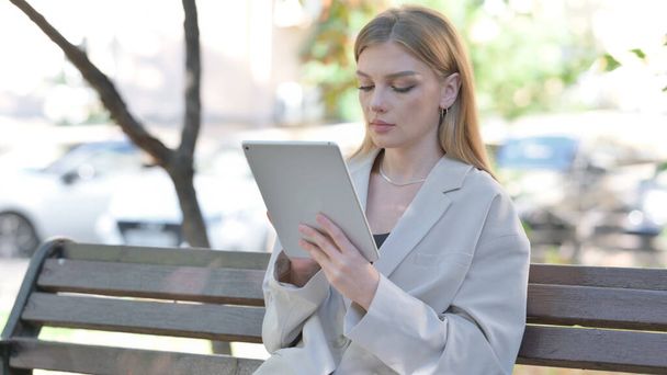 Joven empresaria que usa Tablet mientras está sentada en un banco - Foto, Imagen