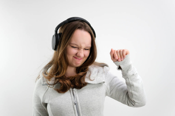 dressing the sleeves of sweatshirts on the thumb teenage girl dancing in headphones fashionably making facial expression fashionable new dances. on a white background - Photo, Image