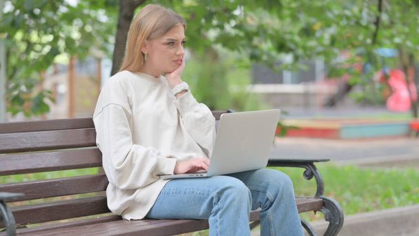 Jeune femme avec mal de dents travaillant sur ordinateur portable en plein air - Photo, image