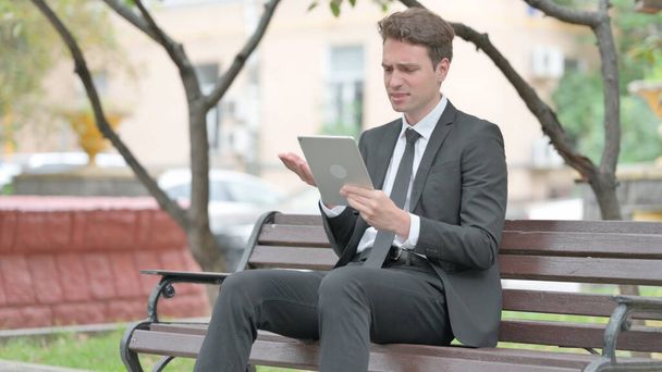 Businessman with Loss on Tablet while Sitting on Bench - Photo, Image