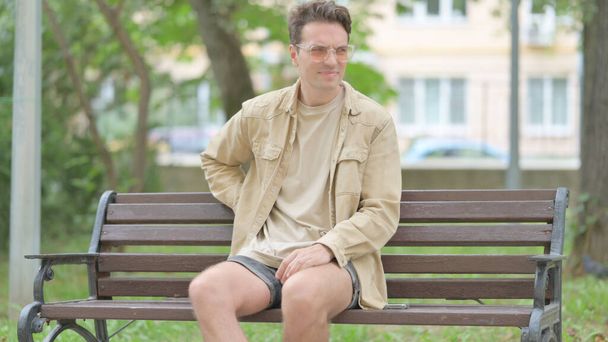 Nenucený mladý muž sedí venku s bolestí zad - Fotografie, Obrázek