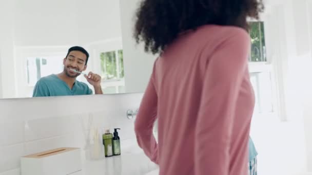 Bathroom mirror, couple and man brush tooth with teeth whitening toothpaste, oral product and morning beauty routine. Home conversation, cavity protection or marriage people consulting on gum hygiene. - Footage, Video
