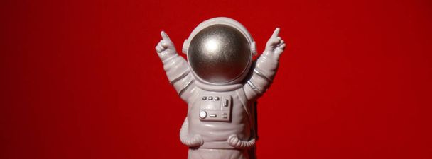 Plastikowy zabawkowy astronauta na kolorowym czerwonym tle Kopiuj przestrzeń. Koncepcja podróży pozaziemskich, prywatne loty kosmiczne. Misje kosmiczne i zrównoważony rozwój - Zdjęcie, obraz