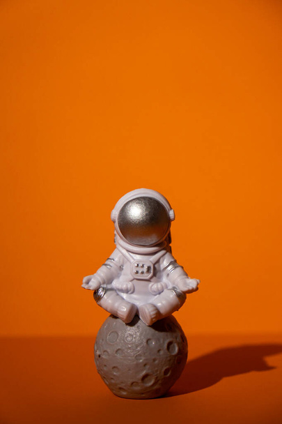 astronauta juguete plástico sobre fondo naranja de colores Copiar el espacio. Concepto de viajes fuera de la tierra, vuelos comerciales de astronautas privados. Misiones espaciales y sostenibilidad - Foto, imagen
