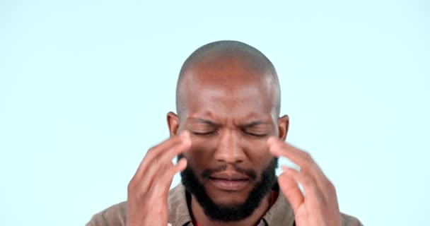 Man, headache and frustrated with pain in studio for stress, vertigo and burnout on blue background. Sick african model with anxiety, fatigue and tired of migraine, brain fog or dizzy with depression. - Filmmaterial, Video
