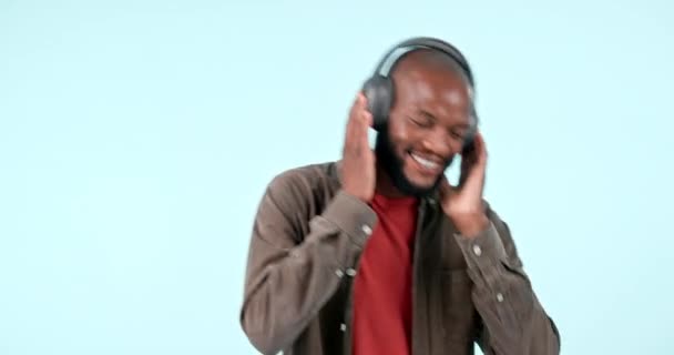 Навушники, танці або щасливий чоловік транслюють музику, щоб розслабитися або звільнитися в студії на синьому фоні. Посмішка, збуджена або африканська людина, що слухає радіо-пісню, звук або звук під час онлайн-підписки. - Кадри, відео
