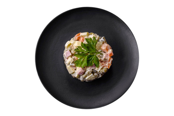 Смачний свіжий салат з олів'є з ковбасою, яйцем, огірком, зеленим горошком, морквою та майонезом. Ситна калорійність їжі
 - Фото, зображення