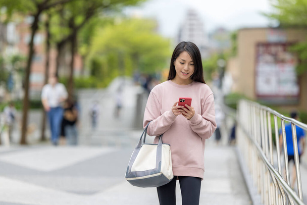 Nainen kävelee kadulla ja käyttää matkapuhelinta - Valokuva, kuva