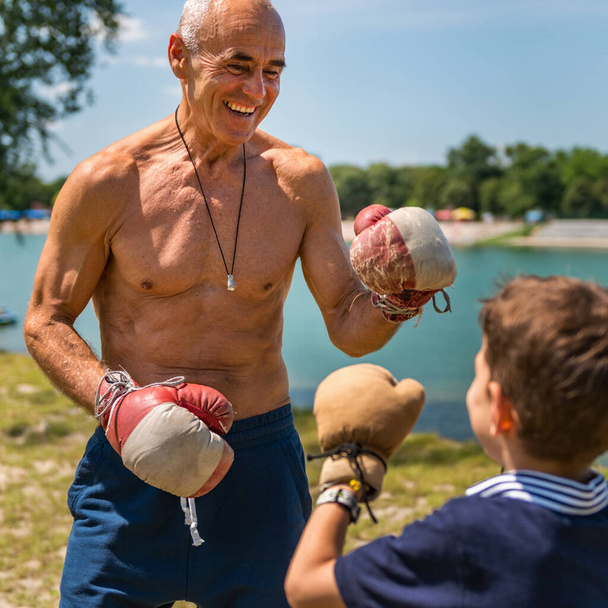 Sportlicher Großvater spult mit seinem begeisterten 8-jährigen Enkel spielerisch, fördert Spaß und Fitness - Foto, Bild