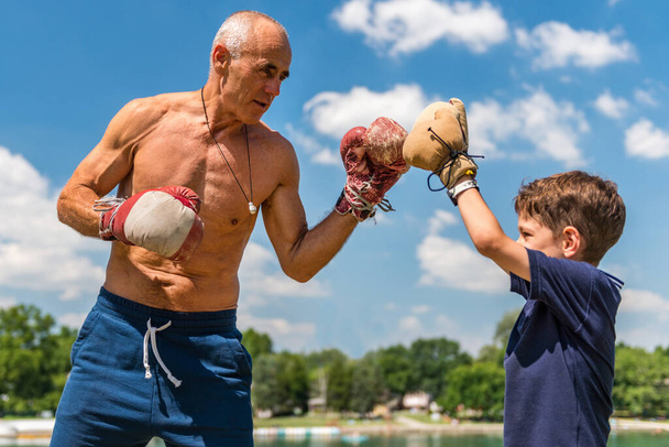 Sportlicher Großvater spult mit seinem begeisterten 8-jährigen Enkel spielerisch, fördert Spaß und Fitness - Foto, Bild