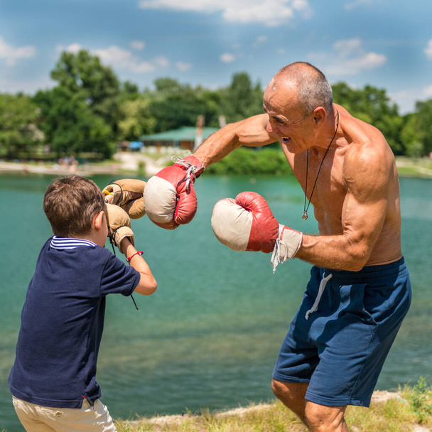 El abuelo atlético juguetona con su entusiasta nieto de 8 años, fomentando la diversión y la aptitud - Foto, Imagen