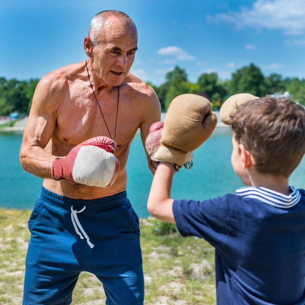 Il nonno atletico scherza scherzosamente con il suo entusiasta nipote di 8 anni, favorendo il divertimento e il fitness - Foto, immagini