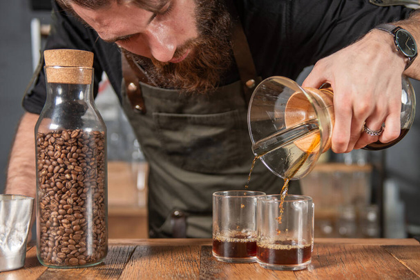 Yetenekli barista titizlikle bir Chemex kahvesi hazırlıyor, bu da bardakları doldurma sanatını gösteriyor. - Fotoğraf, Görsel