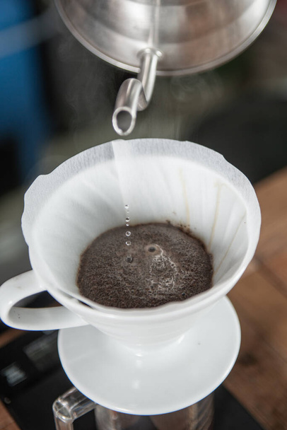 Barista vakkundig met behulp van een druppelkoffiezetapparaat om een smaakvolle kop koffie te maken. - Foto, afbeelding