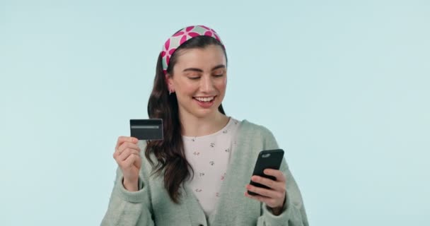 Lächeln, Telefon und Kreditkarte mit einer Kundin im Studio auf blauem Hintergrund für die Bankzahlung. Fintech, E-Commerce oder Online-Shopping mit einem jungen Menschen, der sein Handy für den Einzelhandel oder die Buchhaltung nutzt. - Filmmaterial, Video