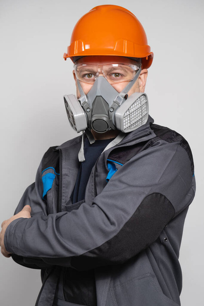 Um homem usando um capacete, respirador e óculos em um fundo branco. - Foto, Imagem