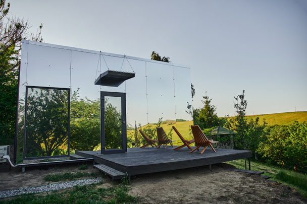 kortárs üvegház fából készült verandával zöld dombok közelében festői vidéken - Fotó, kép
