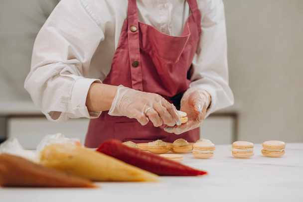 Een banketbakker maakt macarons in een banketbakkerij. Hoge kwaliteit foto - Foto, afbeelding