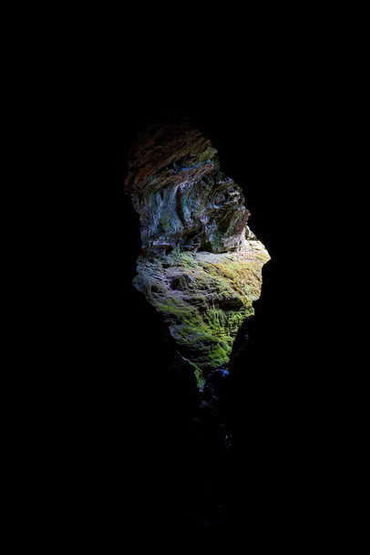 Túrázók jelennek meg egy sötét barlangból a fénybe, a barlang belsejéből nézve, a bejárat keretezi a fényt. - Fotó, kép