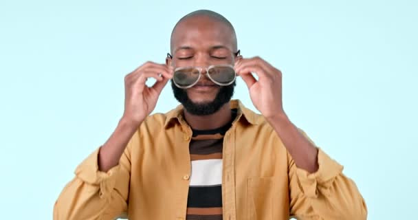 Okulary przeciwsłoneczne, uśmiech i twarz czarnego mężczyzny w studiu o stylowej, chłodnej i modnej modzie. Szczęśliwy, styl i pewny siebie młody afrykański model męski z ostrą twarzą akcesoria izolowane przez białe tło - Materiał filmowy, wideo