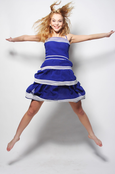young happy woman in blue dress jumping - Fotó, kép