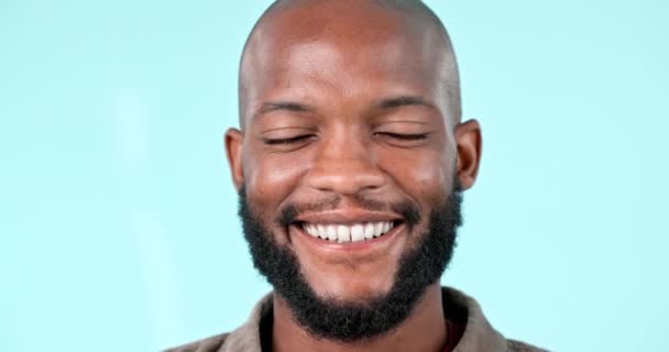 Joyeux, sourire et visage de l'homme noir dans un studio avec une attitude positive, bonne et confiante. Excité, bonheur et portrait headshot de jeune modèle masculin africain avec fierté isolé par fond bleu. - Séquence, vidéo