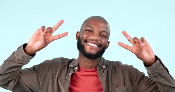 Peace, smile and face of man in studio for winning, success and feedback of vote on blue background. Portrait, african model and emoji of v sign for victory, hope or icon of freedom, support or pride. - Footage, Video
