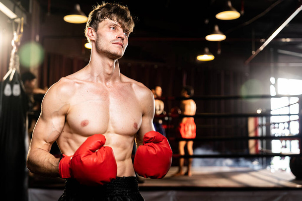 Combattant de boxe pose torse nu, boxeur homme caucasien portant un gant rouge en position de garde défensive prêt à se battre et frapper à la salle de gym avec anneau et équipement de boxe en arrière-plan. Impulsion - Photo, image