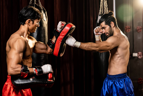 Азійський і кавказький муай-тай боксер вивільняє пунш під час запеклих тренувань з боксу, завдаючи удару тренеру, демонструючи техніку муай-тай і його навички. Імпест - Фото, зображення