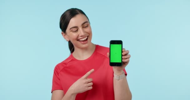 Πράσινη οθόνη, δείχνοντας το χέρι και γυναίκα πρόσωπο με τηλέφωνο στο στούντιο για fitness, app ή εγγραφείτε μπλε φόντο. Smartphone, χώρος και πορτρέτο της κυρίας προσωπικό γυμναστή δείχνουν εφαρμογή, μενού ή διαδικασία. - Πλάνα, βίντεο