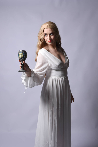 Primer plano retrato de la hermosa modelo rubia con elegante vestido de halloween blanco, un personaje de fantasía histórica. Cáliz de vino, aislado sobre fondo de audio. - Foto, Imagen