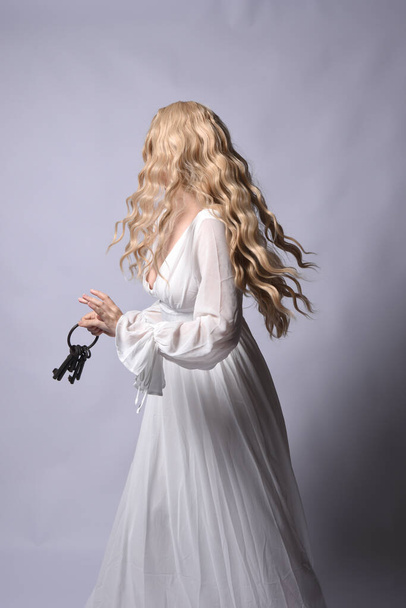 Close up portret pięknej blond modelki w eleganckiej białej sukni halloween. Ramiona sięgające jak głodny wampir. izolowane na tle studia z czerwonym kinowym oświetleniem nastroju. - Zdjęcie, obraz