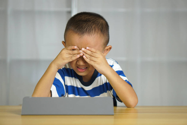 Boy tiene tensión ocular de mirar a la computadora durante mucho tiempo - Foto, imagen