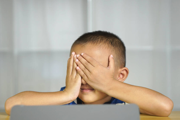 男の子は長い間コンピュータを見ることから目の緊張を持っています - 写真・画像