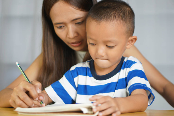 Madre si tiene per mano con il figlio per praticare la scrittura di lettere - Foto, immagini