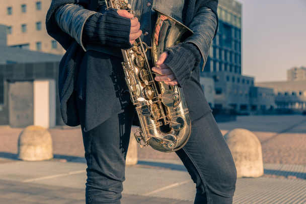 Beautiful young woman with her saxophone - Foto, imagen