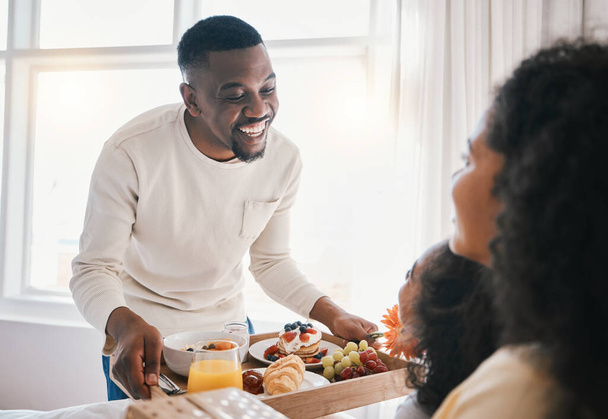 Mothers day, breakfast and family in bed with happy dad, mom and child together in home with love, care and brunch tray. Father, surprise and mom with girl and food in bedroom for special celebration. - Photo, Image