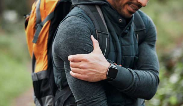 Shoulder pain, hiking injury and person hand outdoor with fitness, workout and travel accident. Athlete, arm bruise and fail from trekking in the woods on a trail with muscle strain and backpack. - Photo, Image