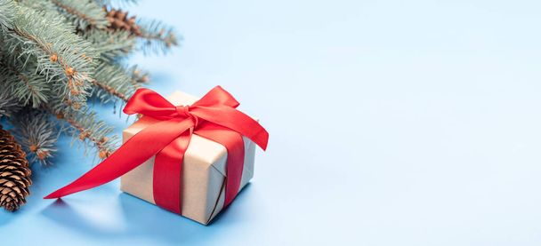 Kerstboom tak en geschenkdoos over blauwe achtergrond met ruimte voor begroeting tekst - Foto, afbeelding