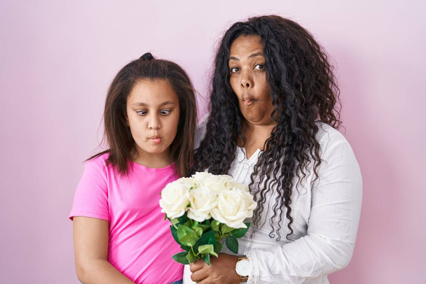 Matka a mladá dcera drží kytici bílých květin, které dělají rybí obličej s ústy a přimhouřenýma očima, bláznivé a komické.  - Fotografie, Obrázek