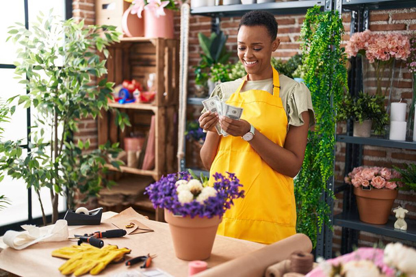 African american woman florist smiling confident counting dollars at florist - Foto, Imagem