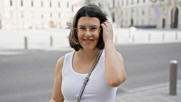 Junge schöne hispanische Frau lächelt selbstbewusst in den Straßen von Wien - Foto, Bild