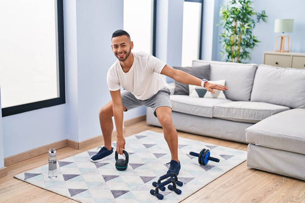 African american man smiling confident using kettlebell training at home - Foto, immagini