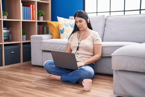 Νεαρή Ισπανίδα γυναίκα που χρησιμοποιεί φορητό υπολογιστή στο σπίτι σκέφτεται στάση και νηφάλια έκφραση που αναζητούν αυτοπεποίθηση  - Φωτογραφία, εικόνα