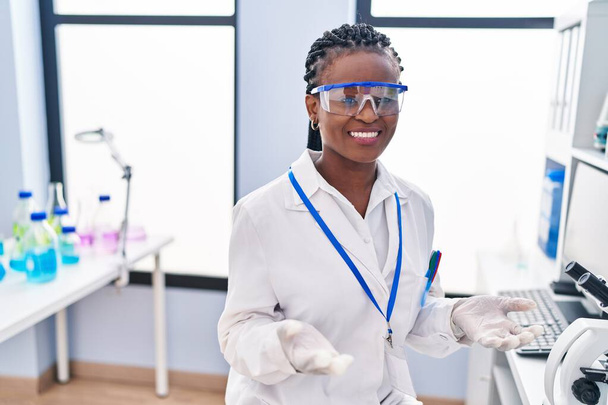 Femme scientifique afro-américaine souriante confiante parlant au laboratoire - Photo, image