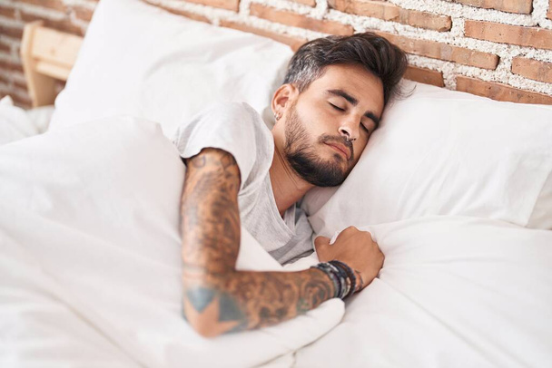 Молодий іспаномовний чоловік лежить на ліжку спить у спальні
 - Фото, зображення