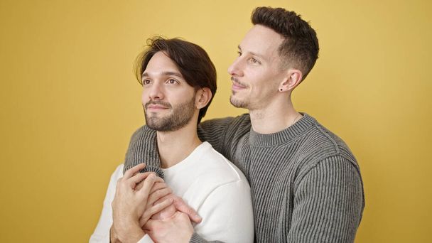 Two men couple hugging each other standing with relaxed expression over isolated yellow background - Foto, Imagem