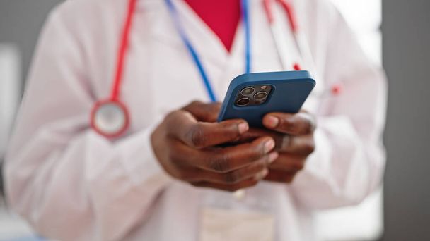 Médico afroamericano usando smartphone en clínica - Foto, imagen