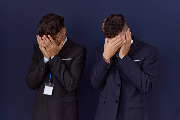 Dos hombres de negocios hispanos que usan ropa de negocios con expresión triste cubriendo la cara con las manos mientras lloran. concepto de depresión.  - Foto, imagen